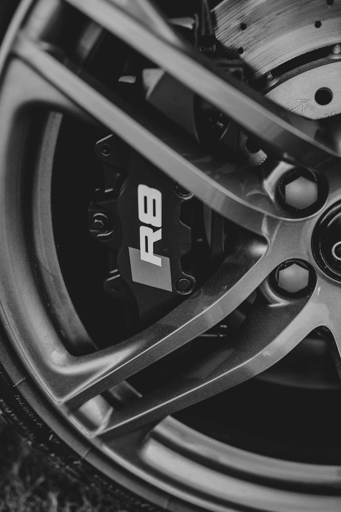 Detailed view of a car brake caliper and wheel rim in black and white.