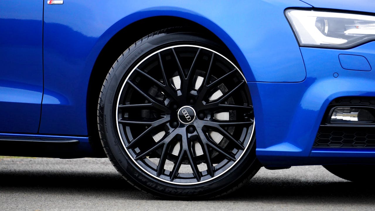services-04 Detailed close-up of a blue Audi car rim and tire, showcasing design and style.