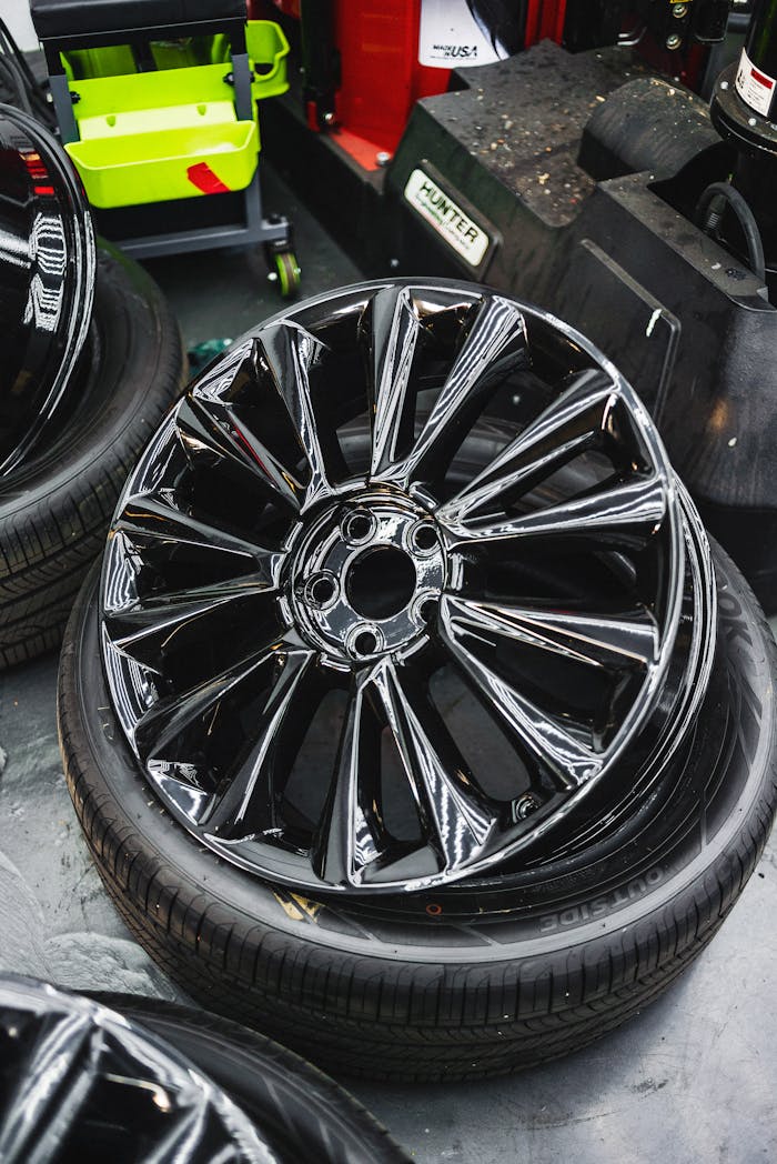 about-bg Glossy black car wheel rim and tire stack in an automotive workshop.