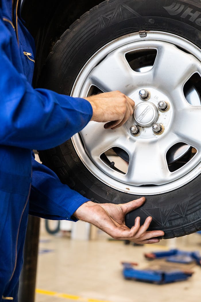 who-we-are A mechanic tightens bolts on a car wheel in a professional garage setting.